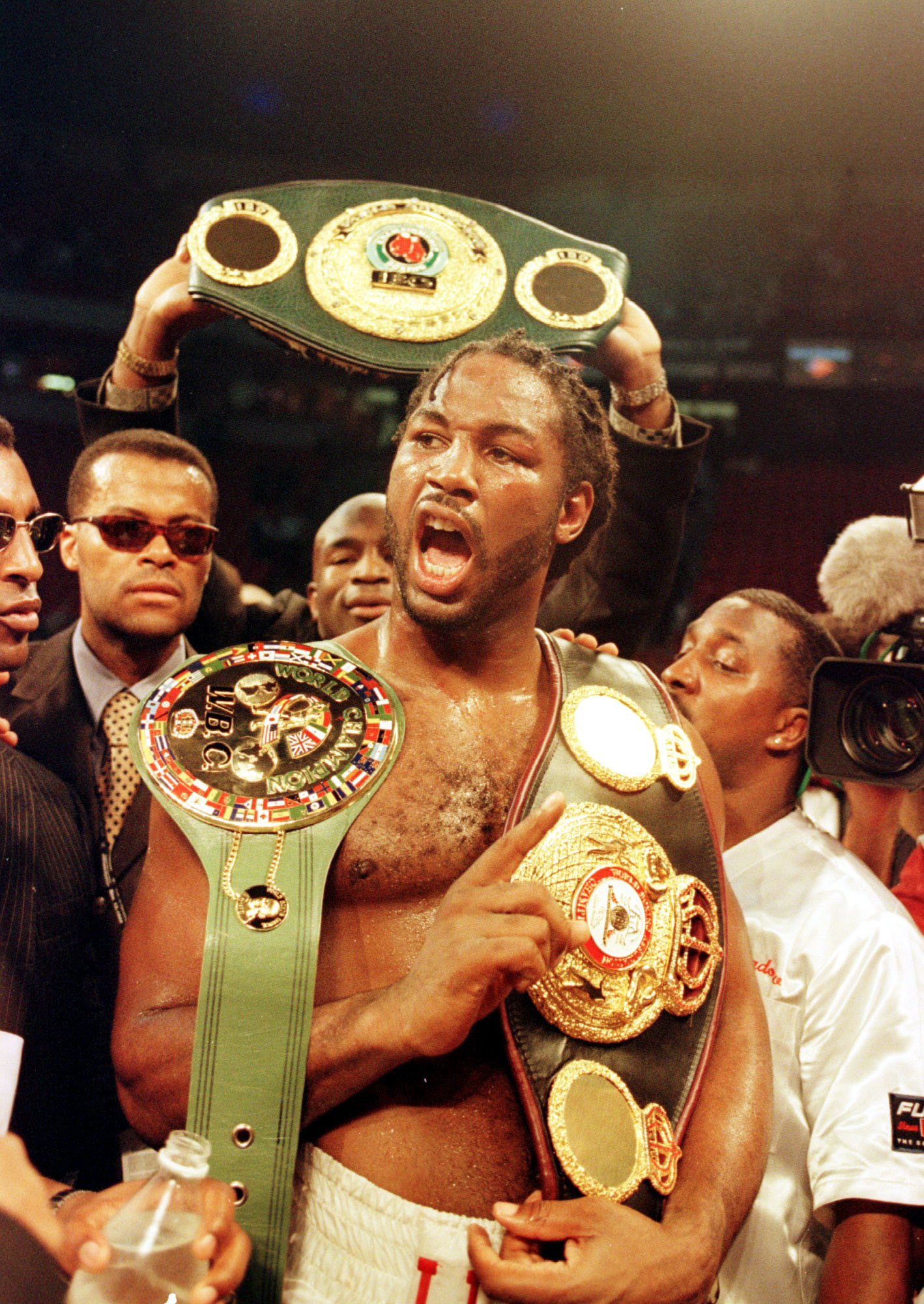 Lennox Lewis celebrates with all three championship belts after winning the World Heavyweight Championship unification fight against Evander Holyfield