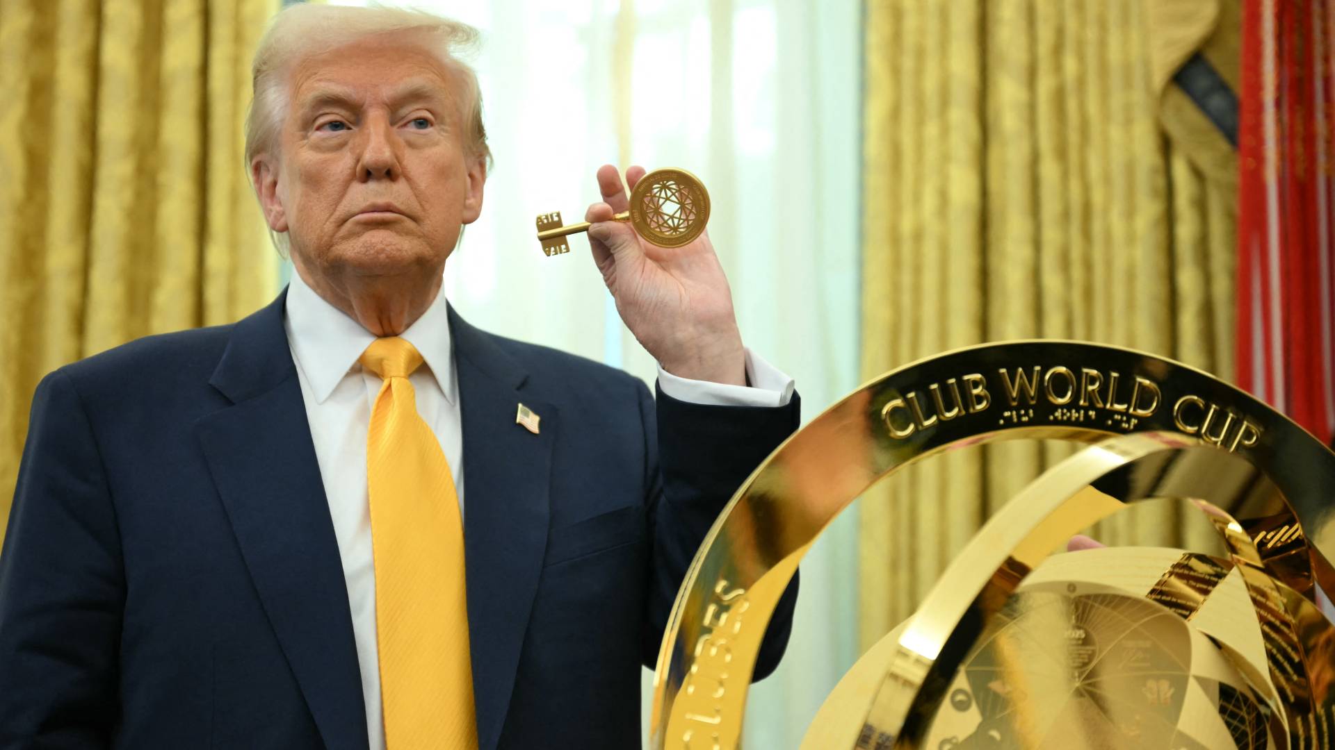 US President Donald Trump holds the key to unlock the new FIFA Club World Cup trophy in the Oval office of the White House